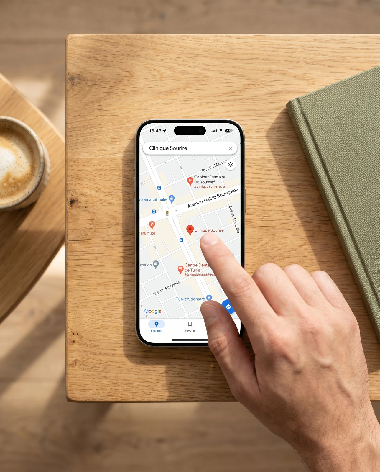 Smartphone affichant Google Maps avec plusieurs cabinets dentaires à Tunis, doigt sur le point de toucher une fiche.